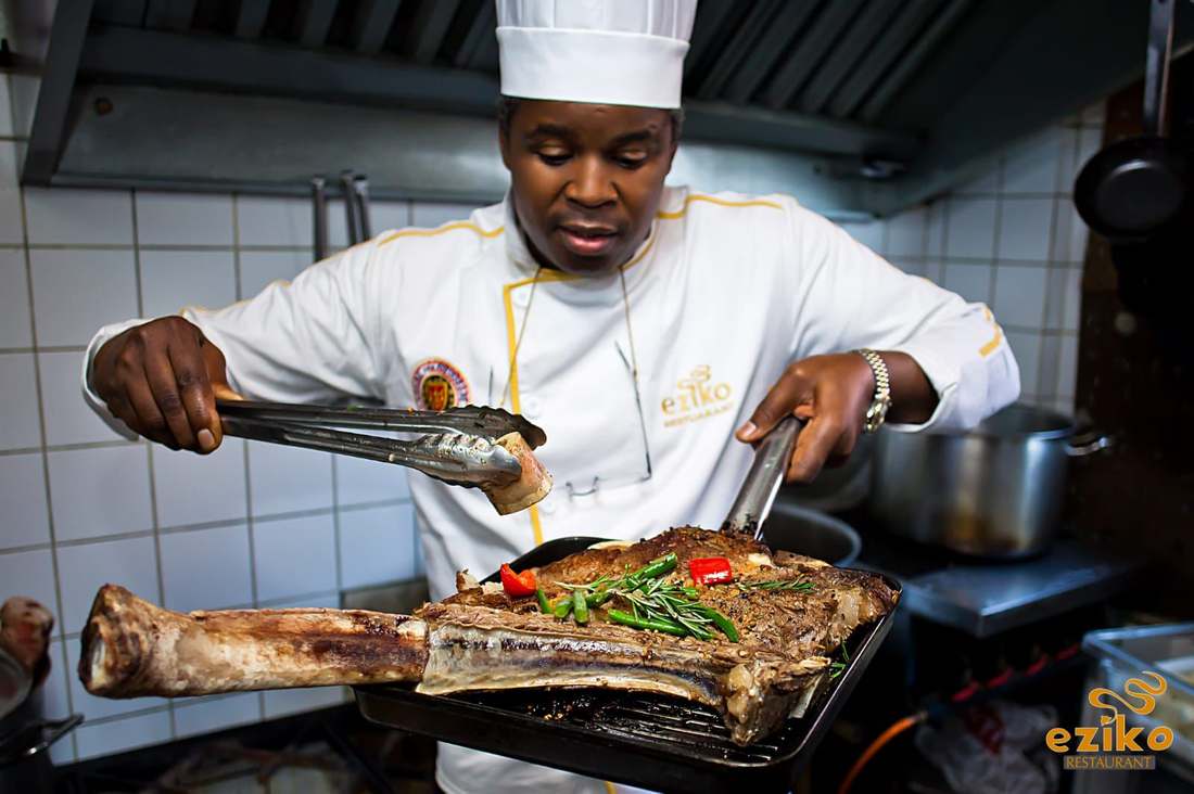 Chef Andile searing a tomahawk steak in the kitchen