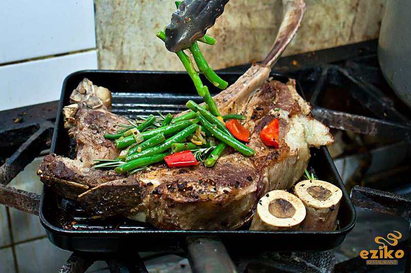 Tomahawk steak on the grill with green beans and bone marrow