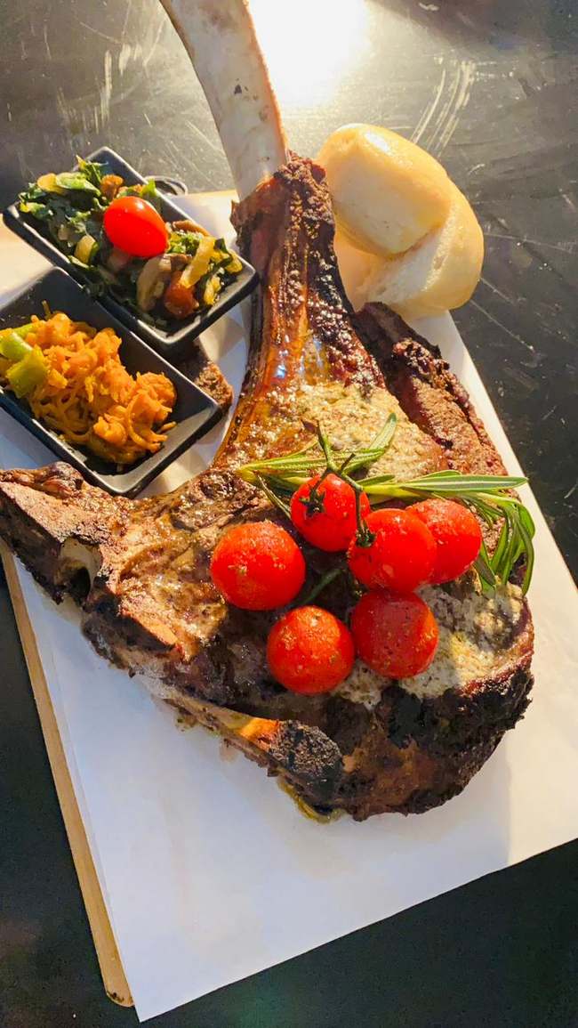 Plated tomahawk steak with roasted cherry tomatoes and pap